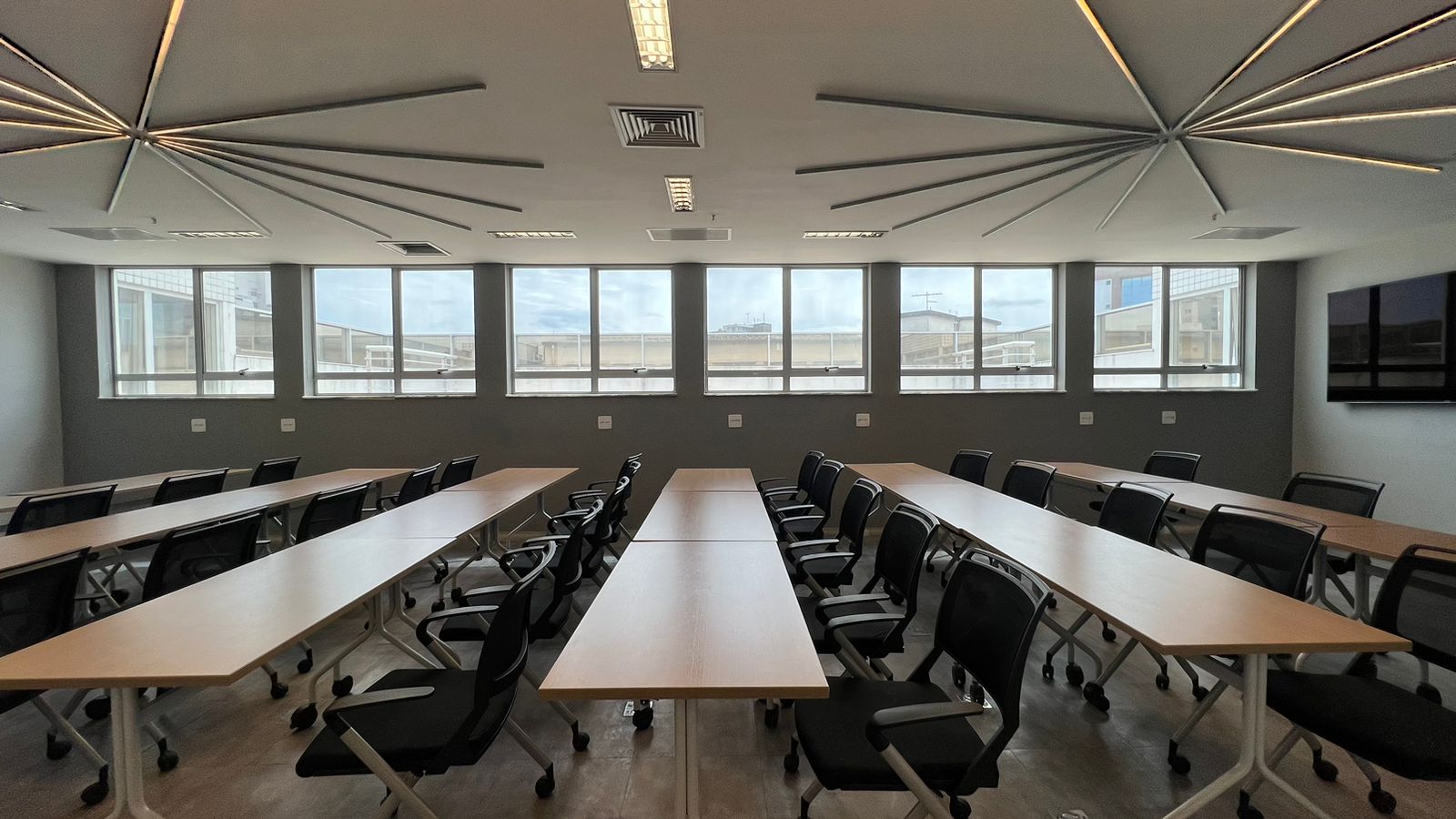 Sala de treinamento com mesas em formato de U e vista para a cidade