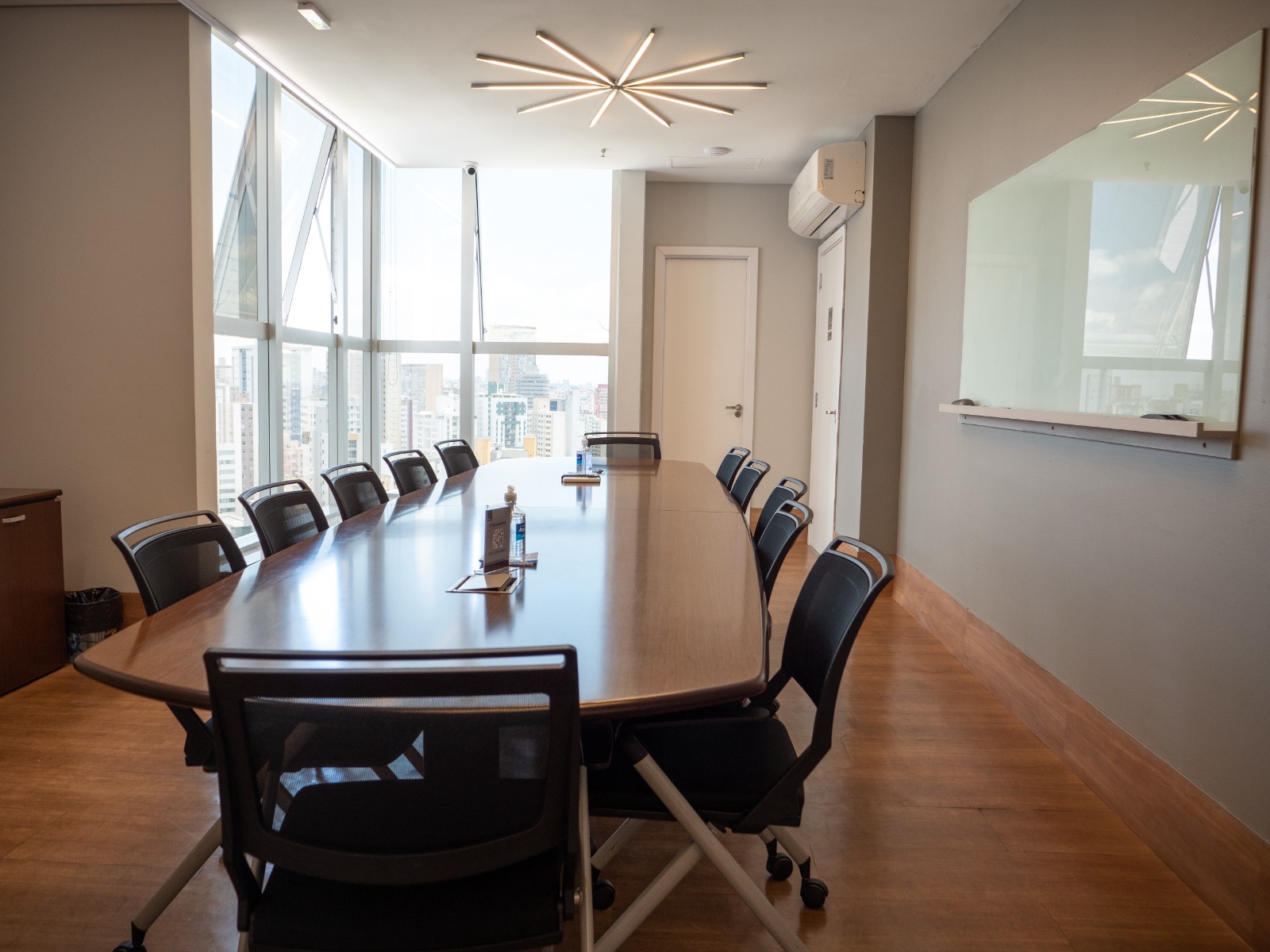 Sala de reunião com mesa oval e vista panorâmica da cidade