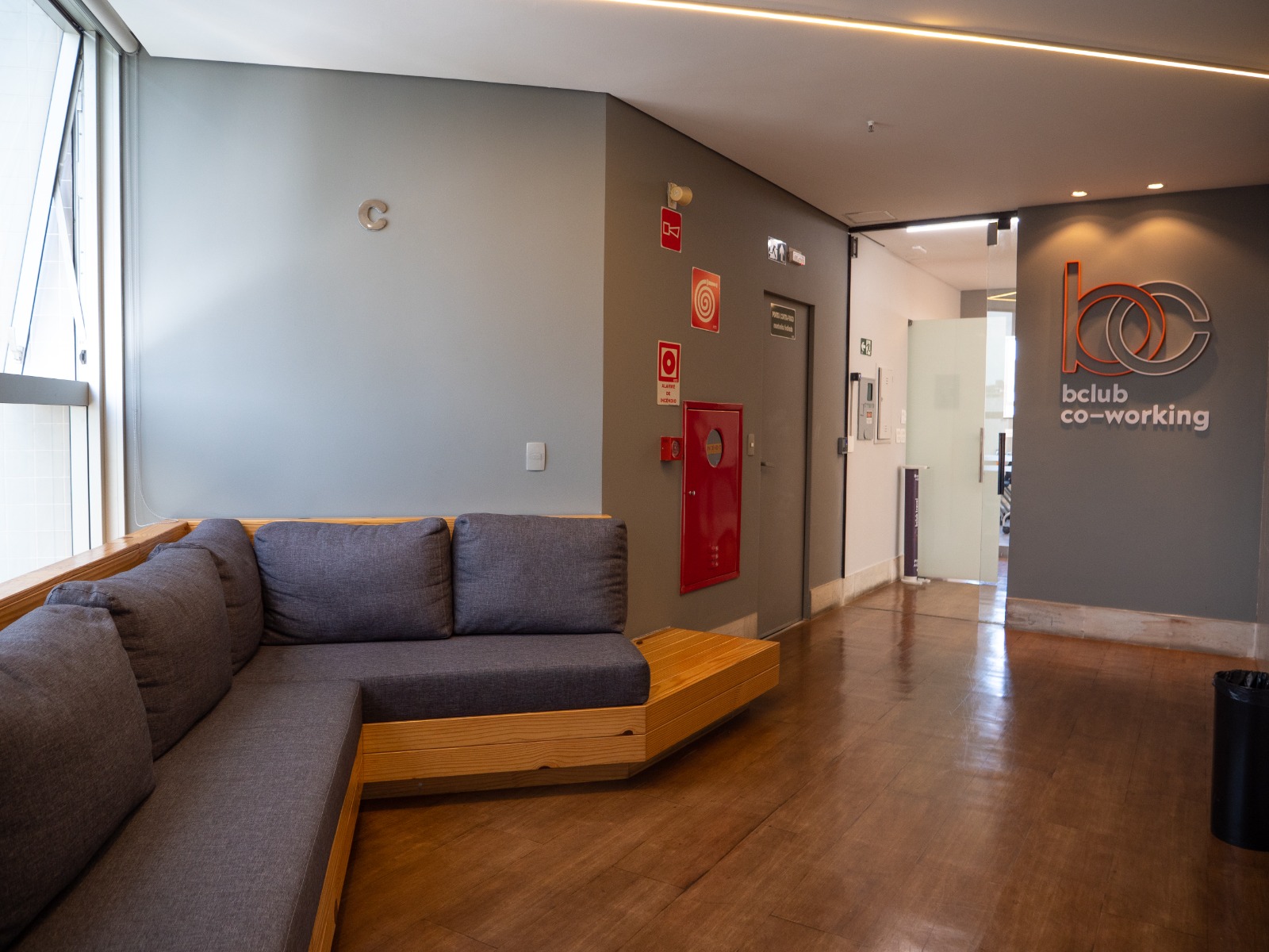 Recepção do coworking com sofá e sinalização do espaço
