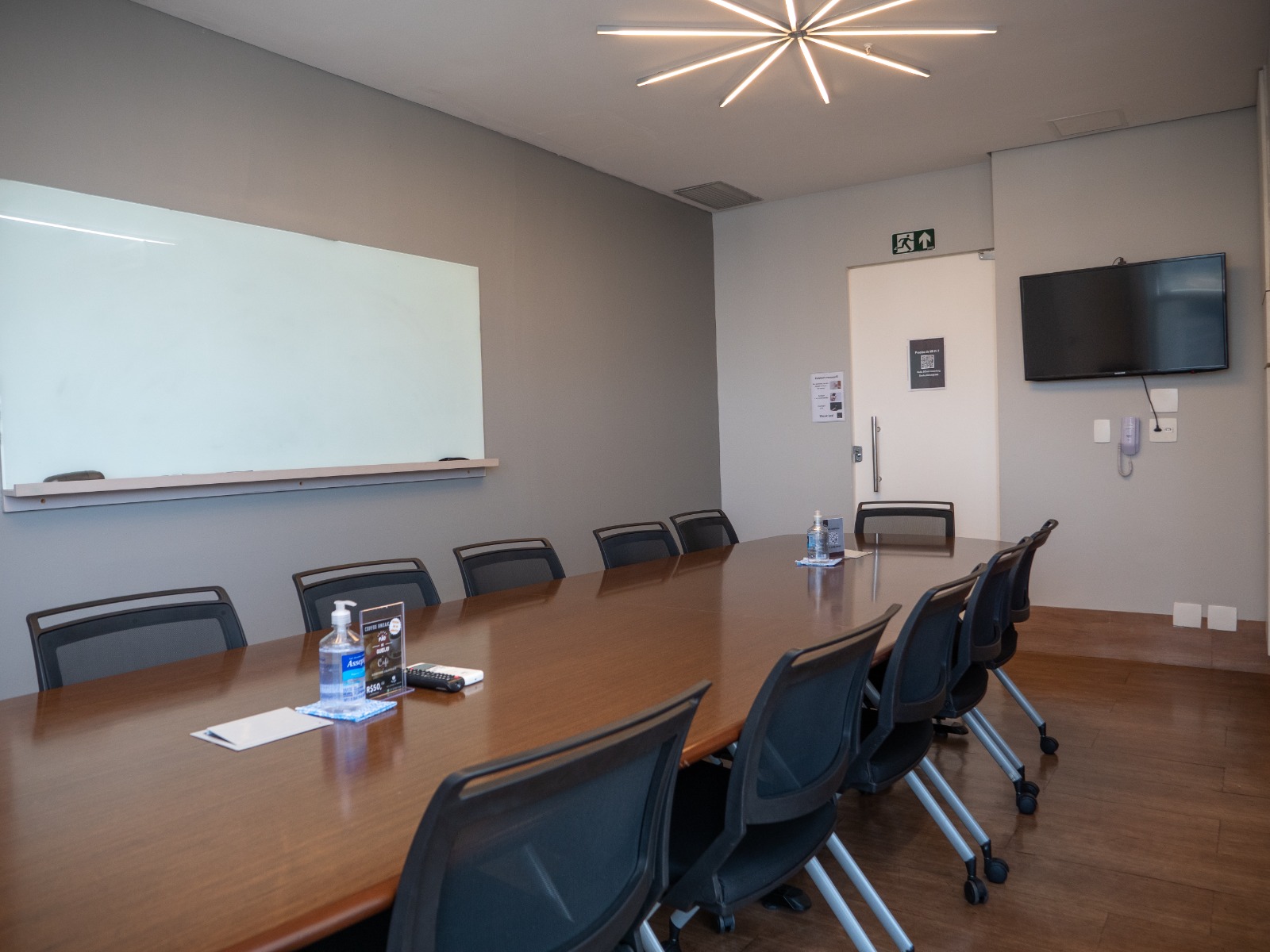 Sala de reunião com quadro branco, TV e mesa oval