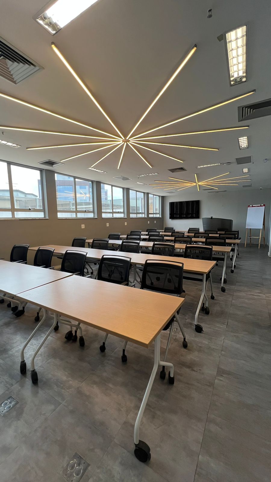 Sala de treinamento do Top Hill Tower com mesas, cadeiras e iluminação linear no teto